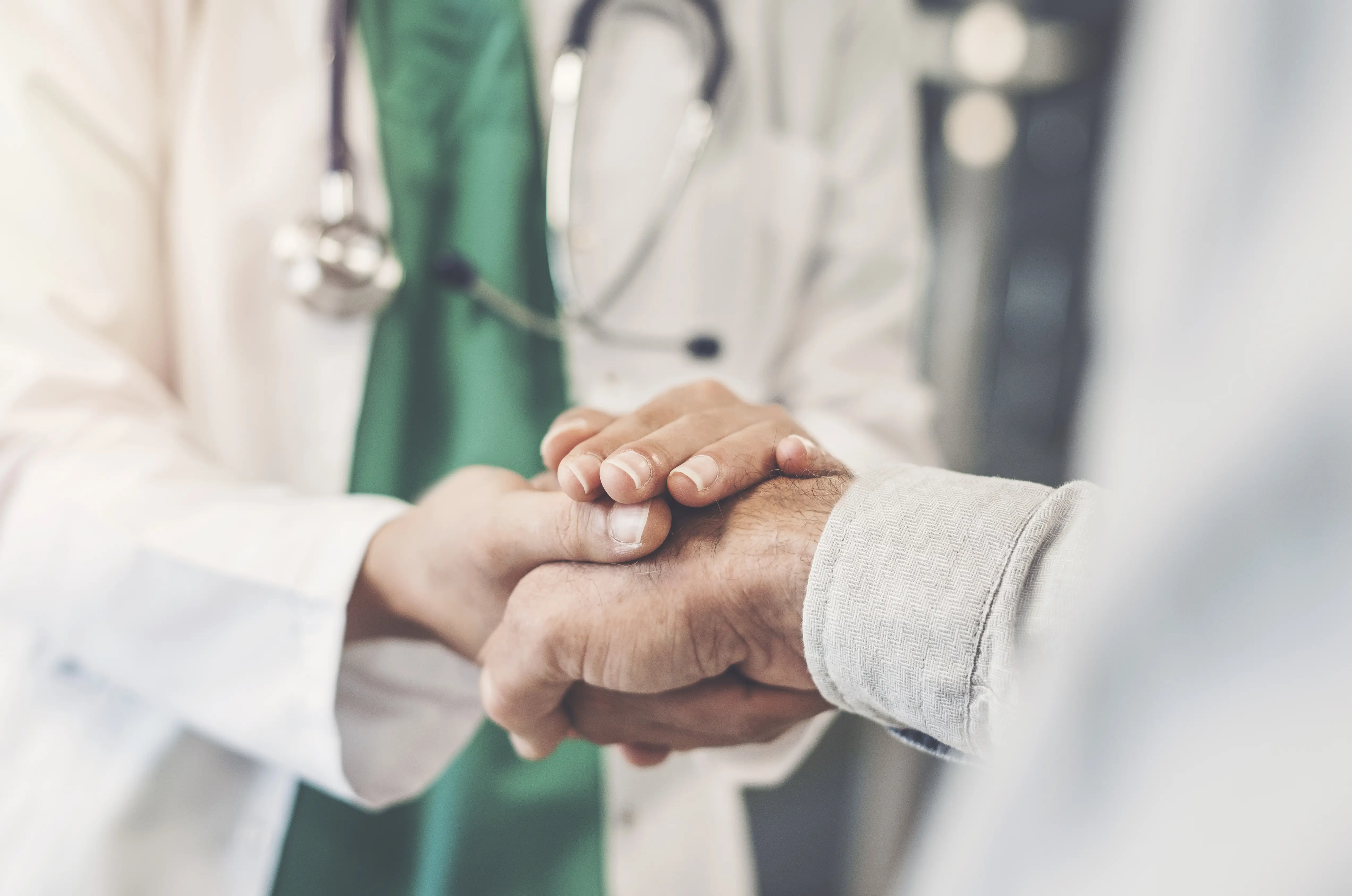 A doctor holding a patient's hand.